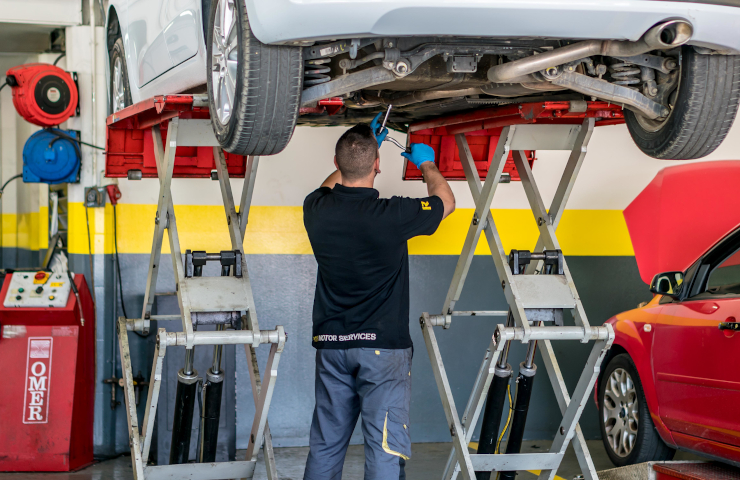 Mecánico de Rodi Motor Services en taller trabajando bajo un coche