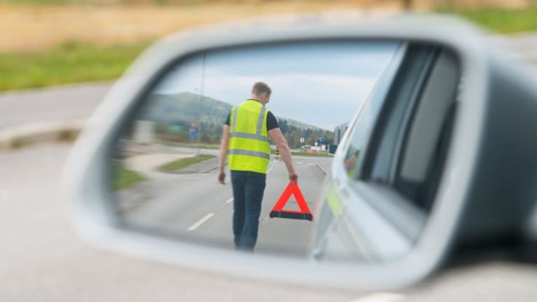 Señor señalizando una avería en carretera con el chaleco reflectante